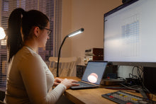 Load image into Gallery viewer, Electra table lamp on a student's desk with a woman working on a lamp