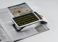 Load image into Gallery viewer, Eschenbach's Smartlux Digital magnifying text from a magazine with yellow on black text for increased.contrast
