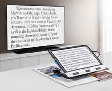 Load image into Gallery viewer, Visolux Digital XL FHD, digital magnifier with large screen, black outer casing and black selection buttons along the bottom of screen, plugged into and transmitting image onto television screen.