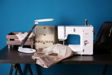 Load image into Gallery viewer, Daylight's Foldi Go on a desk with a sewing machine.