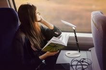 Load image into Gallery viewer, Woman using Daylight's Foldi Go on a train to read.