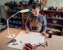 Load image into Gallery viewer, Man using Daylight's Tricolour lamp in a workshop to see design on paper.