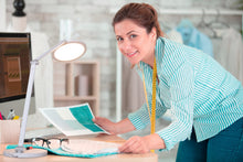 Load image into Gallery viewer, A woman using Daylight's Tricolour lamp to tailor clothes.