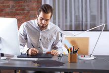 Load image into Gallery viewer, Man using Daylight's Tricolour lamp at a desk.