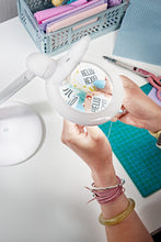 Load image into Gallery viewer, Lady crafting, holding a pattern with writing on it under the lens of a Halo Magnifying lamp
