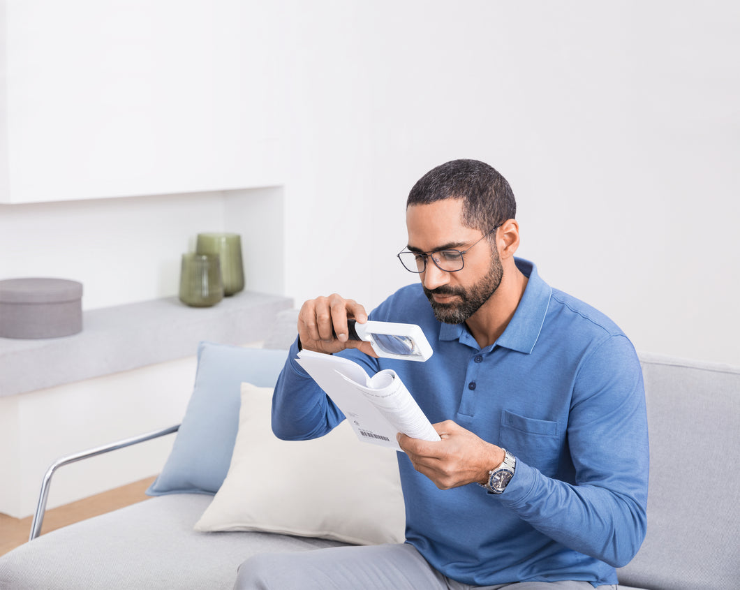 Young man using rectangular mobilux LED to aid reading  