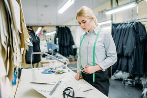 Woman using Slimline table lamp at work for altering clothing.