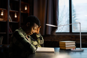 Person reading a book using the Daylight's Tricolour lamp.