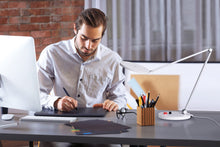 Load image into Gallery viewer, Man using Daylight&#39;s Tricolour lamp at a desk.
